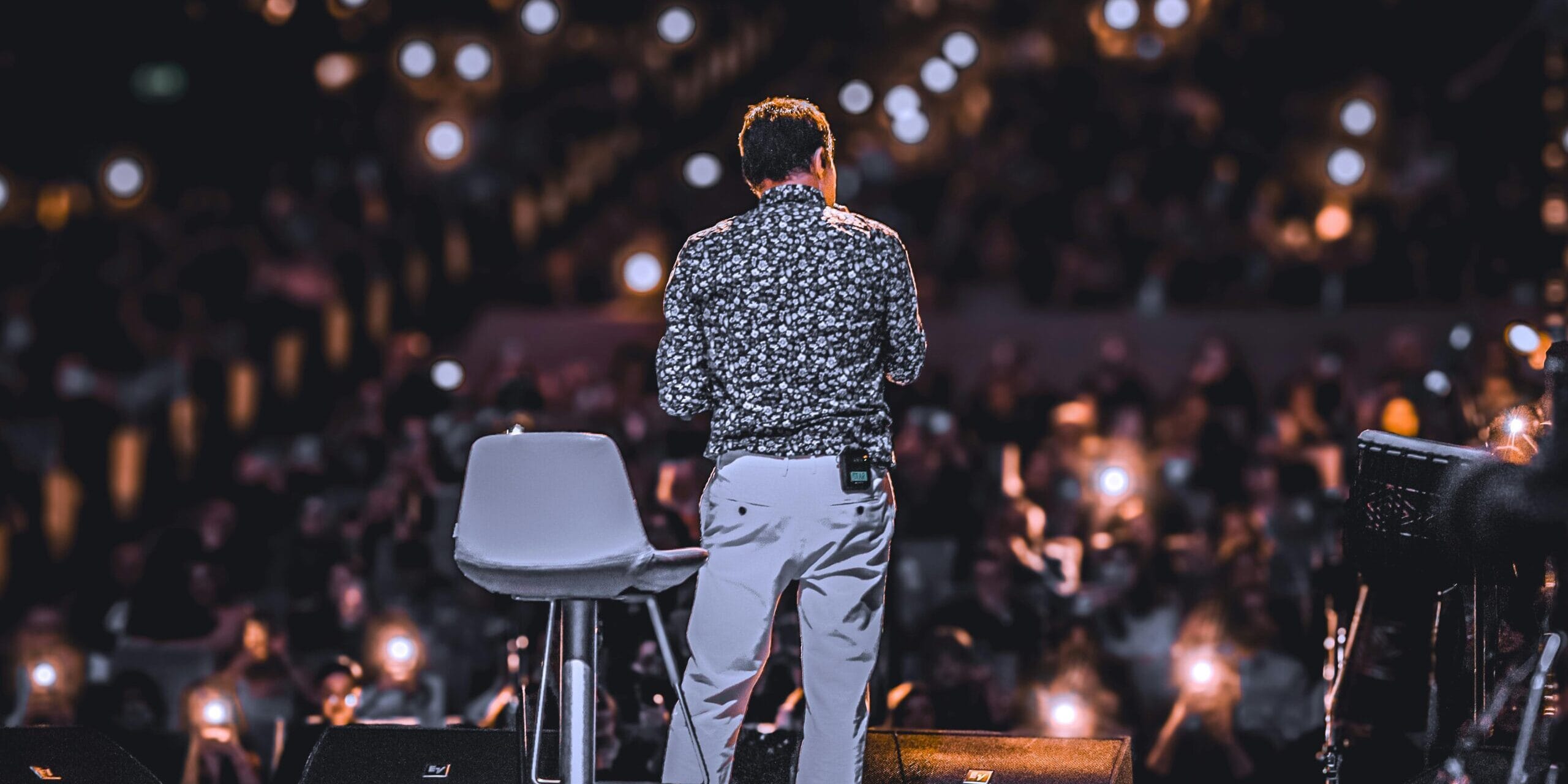 Imagine cu un tip pe scena vorbind in fata unui amfiteatru plin